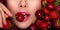 Attractive woman tasting cherry and strawberry. Beautiful woman with fashion makeup and a vivid background