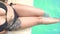 Attractive woman with tattoo sitting on poolside top view. Beautiful woman splashing water by tanned legs in swimming