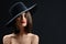 Attractive woman wearing a hat posing on black background