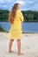 Attractive woman in yellow outfit on river beach