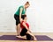 Attractive yoga therapist teacher helping beginner young woman with yoga exercise in studio home