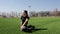 Attractive young active fit woman does yoga stretch pose on huge stadium green grass meditating calmly on warm sunny day