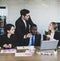 Attractive young adult caucasian businessman leader consulting with concentrated multiracial colleagues that gathered in front of