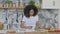 Attractive Young African Woman Peeling Cucumber in Kitchen