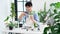 Attractive Young Asian man taking care Water the household plants pots near window, Gardening at Home concept