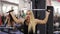 Attractive young blond caucasian woman with sporty body performing weightlifting on a lat pull-down mashine at the gym