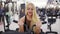 Attractive young blond woman with sporty body pumping up biceps muscles on training set in the gym. Doing excercises