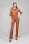 Attractive young blonde model with perfect slim body posing in trendy orange pantsuit full length