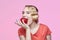 Attractive young blonde with a retro hairstyle is about to bite a red apple