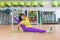 Attractive young brunette female athlete doing advanced split stretching exercise for legs smiling looking at camera