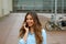 Attractive young business woman talking on her phone while standing in courtyard of office blocks. Cheerful business woman outdoor