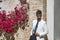 Attractive young businessman with beard, suit and tie, posing leaning against a brick wall with a background of flowers. Concept