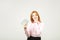 Attractive young businesswoman posing with bunch of USD cash in hands showing positive emotions and happy facial expression.