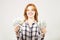 Attractive young businesswoman posing with bunch of USD cash in hands showing positive emotions and happy facial expression.