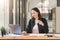 An attractive, young, and confident mixed-race asian businesswoman is sitting at the office table, enjoying an espresso