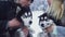 Attractive young couple holds and hugs two beautiful siberian huskies and discuss something in snowy winter forest. Dogs