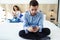 Attractive young couple ignoring each other using phone after an argument while sitting on bed at hotel room