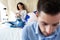 Attractive young couple ignoring each other using phone after an argument while sitting on bed at hotel room