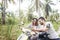 Attractive young couple on motorbikes in the jungle are looking for a way in the map in the smartphone, honeymoon in tropical