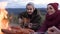 Attractive young couple sitting near fire and playing on the guitar on the mountain backgrounds.