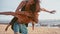 Attractive young and energetic couple having fun on the beach. Woman piggyback riding a man and laughing. Sea Summer