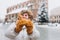 Attractive young female tourist in yellow hat is holding pretzel, traditional polish bagel on Market Square in Krakow