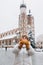 Attractive young female tourist in yellow hat is holding pretzel, traditional polish bagel on Market Square in Krakow