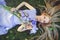 Attractive young girl with blonde dren hair and natural make-up smelling blue purple iris flowers lying on grass outdoors, tendern