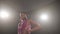 Attractive young girl dancing latino solo in a dark room with smoke in a low key. Professional ballroom sports dancing