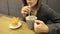 Attractive young girl in glasses drinks coffee coconut latte through a straw sitting in a cafe.