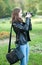 Attractive young girl taking pictures outdoors. Cute teenage girl in blue jeans and black leather jacket taking photos in park