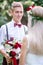 Attractive young groom in blue braces stands before bride