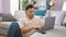 Attractive young hispanic man, concentrated and serious, sitting on the floor in his cozy apartment, working online on his laptop,