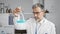 Attractive young hispanic man, grey-haired chemist, concentrating on measuring liquid in test tube at indoor science lab