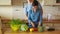 Attractive young housewife standing at kitchen table and cutting vegetables. Her husband comes up, hugs and kisses his