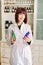 Attractive young lady pharmacist with a lovely smile standing working and holding glass vintage bottles of medicines in