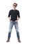 Attractive young macho redhead man standing with hands in jeans pockets wearing black shirt and sunglasses