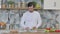 Attractive Young Man Peeling Cucumber in Kitchen