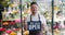 Attractive young man wearing apron holding open sign in flower store smiling
