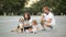 Attractive young mother, bearded father, cute little daughter and beagle dog are sitting on the city square during their