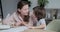 Attractive young mother studying with her kid pupil at home and teaching him how to count and write.