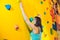 Attractive young professional sport climber woman having training in the gym at artificial wall