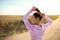Attractive young sportswoman ties her hair in a ponytail before jogging along a deserted country steppe road