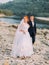 Attractive young wedding couple. Shore of a mountain river with stones on background