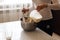 Attractive young woman adding milk to the flour