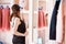 Attractive young woman in black pajamas is choosing clothes in light room. Girl in wardrobe