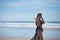 Attractive young woman in black swimsuit and sarong, lonely and quiet, walking on the beach. Concept tranquility, peace, wind,