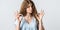 Attractive young woman with curly long hairstyle shows OKAY sign with both hands