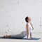 Attractive young woman doing urdhva mukha svanasana in white loft