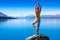 An attractive young woman doing a yoga pose for balance and stretching near the lake